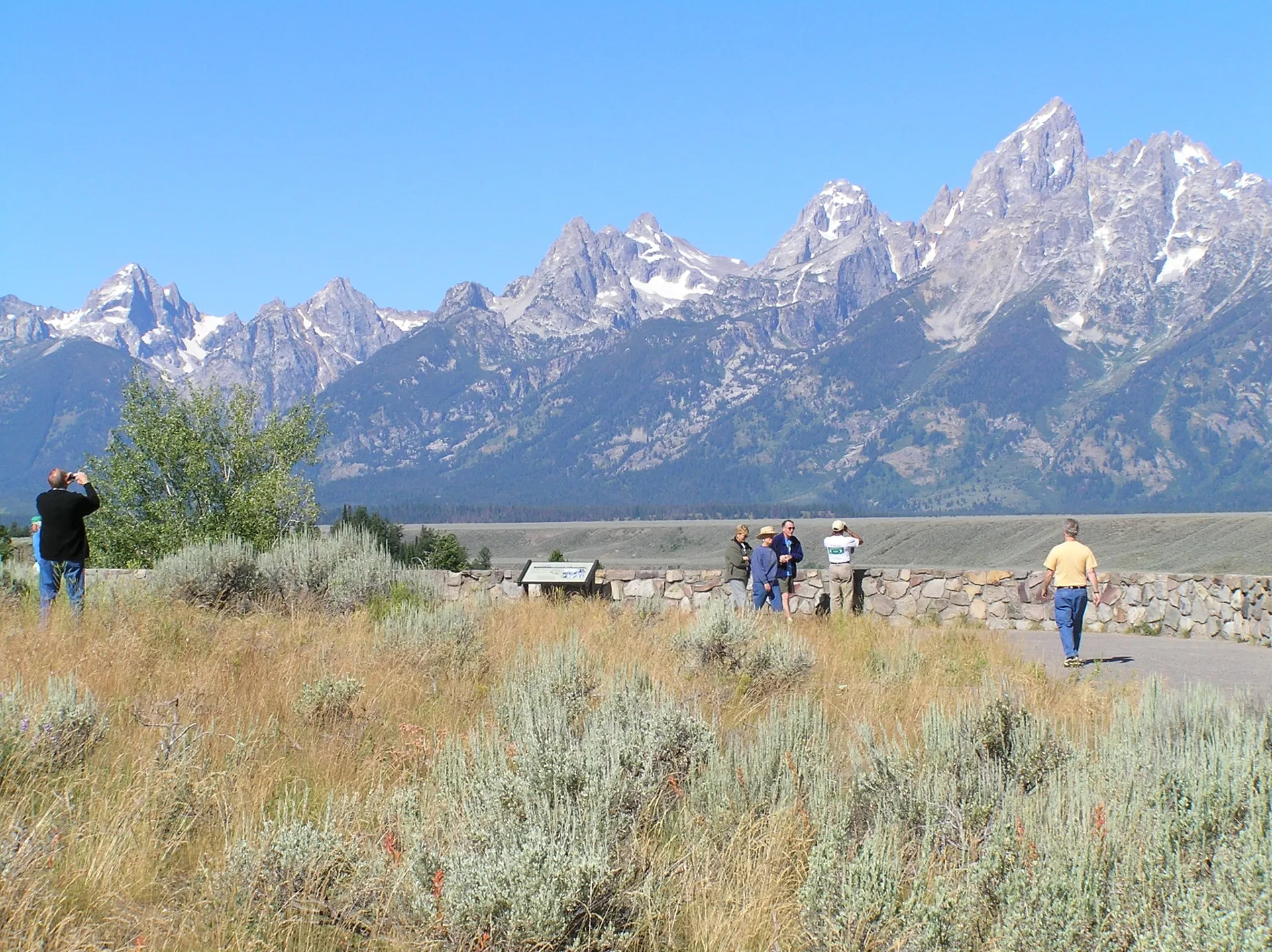 Visitors looking across sagebrush and the Snake River valley toward the Teton Range