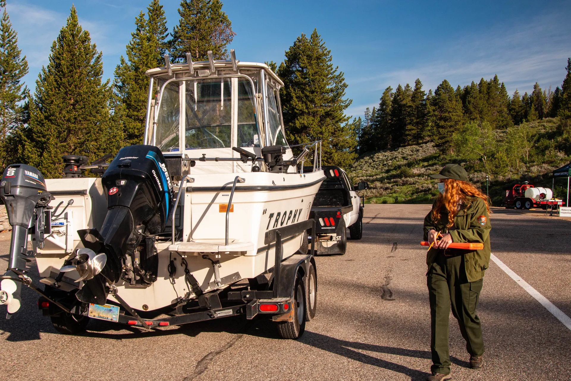 Staff conducting an aquatic invasive species inspection beside a small boat